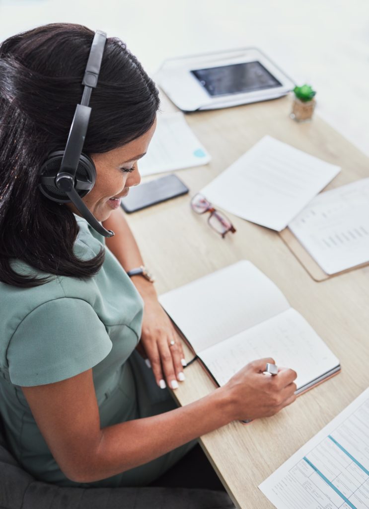 Customer support, call center and black woman writing in notebook for schedule, planning and feedba